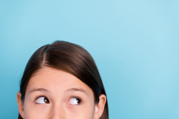年轻好奇女孩在蓝色背景上凝视空旷空间的剪裁照片，适合广告创意。图片下载