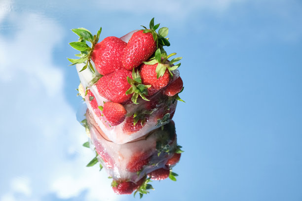 创意夏季概念，新鲜草莓被冰冻在镜子上，映照出天空。明亮、清新的食物照片，采用自然光和鲜艳的色彩。留白空间。图片下载