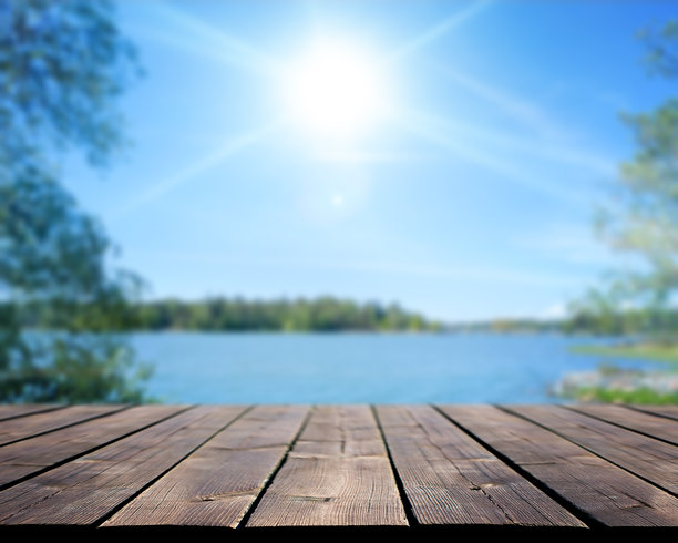 湖景木甲板。阳光明媚的夏季背景，模糊的水面和天空。库存照片。图片下载