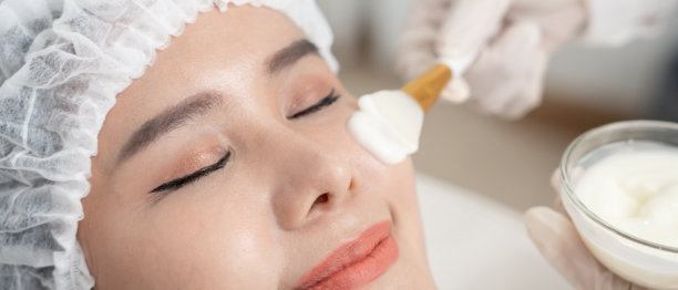 美丽的女性正在接受面部水疗和护理。健康女性的面部涂抹面霜。皮肤霜的广告，抗皱、婴儿般的面容、美白、保湿、收缩毛孔精华。图片下载