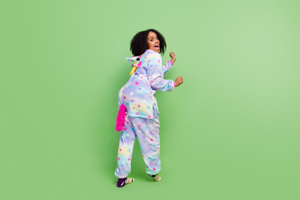 全身背面照片，展现一位童趣的女士在温暖的动漫睡衣派对上跳舞，背景为绿色。图片下载