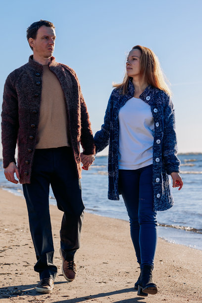 恩爱情侣在阳光明媚的秋日海滩上漫步。周末与生活方式的概念。竖版照片图片下载