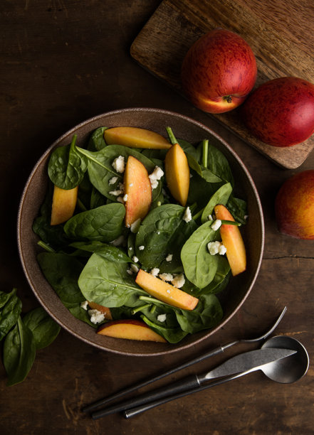 新鲜夏季沙拉，配有桃子、菠菜、微型绿叶菜和菲达奶酪，背景为木质纹理。健康饮食，清淡饮食，佛碗沙拉，俯视图。图片下载