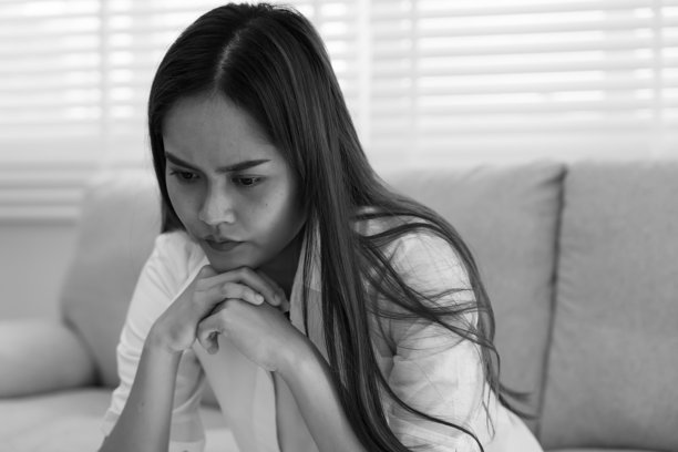 单色照片，抑郁和心理疾病。亚洲女性因收到坏消息而感到失望和悲伤。压力大的女孩因意外怀孕而感到困惑，哭泣并担忧不幸的问题。图片下载