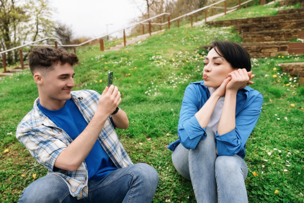 年轻情侣在春天的阳光下午，在公园里享受轻松的一天，拍摄有趣的照片，快乐地在一起。图片下载