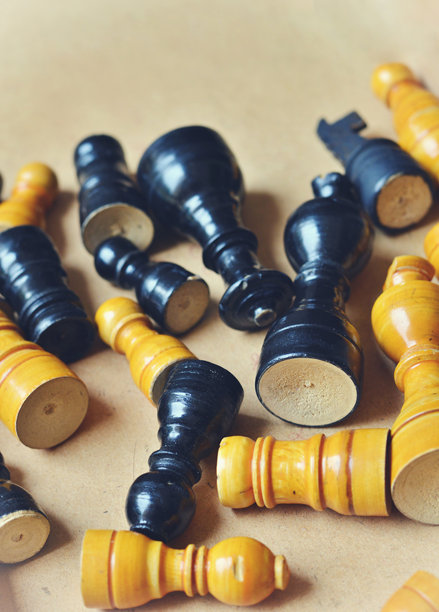 从顶部视角或正上方视角拍摄的垂直照片，展示了散落在米色纸板背景上的混乱木制棋子，具有选择性焦点和棕色留白空间。图片下载