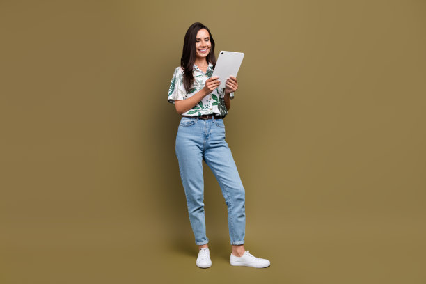 全身照片，漂亮的女企业经理使用平板电脑与同事沟通，背景为棕色。图片下载