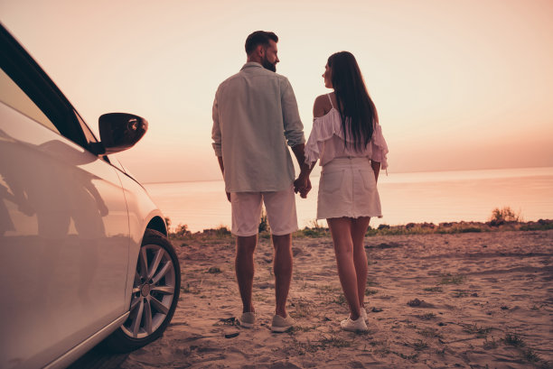 夫妻在户外海边手牵手，展现浪漫情感的全身背影照片图片下载