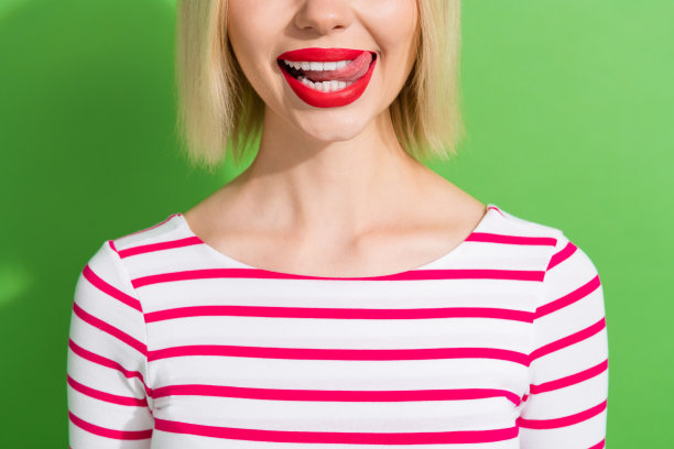 特写剪裁照片，展示一位迷人的短发女性，穿着条纹衬衫，舌头舔着牙齿，背景为绿色。图片下载