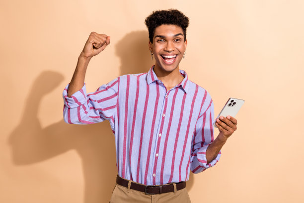 吸引人的年轻男性的照片肖像，举起拳头，穿着时尚的条纹正装，背景为米色。图片下载