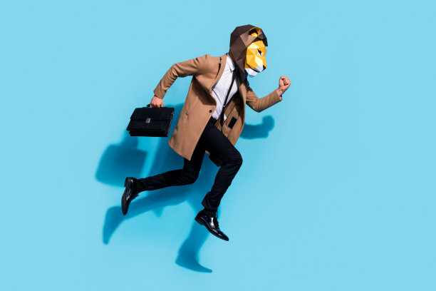 穿着狮子面具的奇怪男子全身侧面照片，跳跃奔跑，迟到参加老板的会议，手里拿着包，背景为蓝色。图片下载