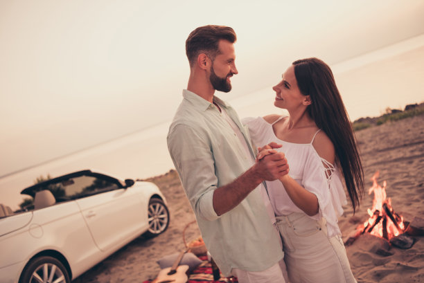 穿着白色衣服的甜蜜闪亮已婚夫妇在乡间公路上开车、跳舞、微笑的照片图片下载