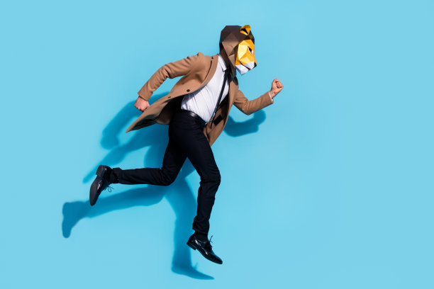 穿着狮子面具的奇特真实男子在蓝色背景下跳跃，急匆匆地参加活动折扣的全身侧面照片图片下载