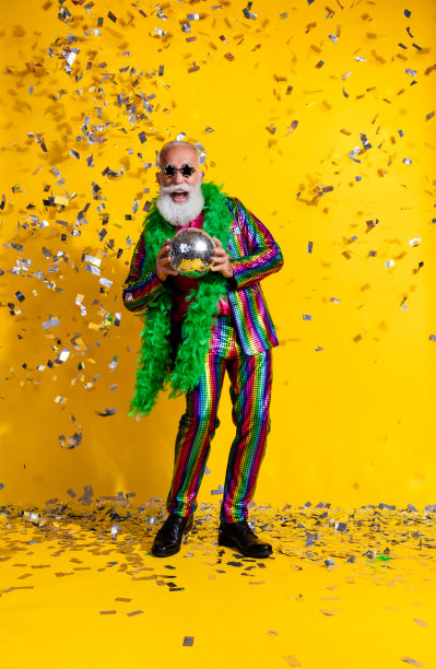全身竖版照片，奢华男子手持迪斯科球，穿着闪亮的服装，背景为黄色。图片下载