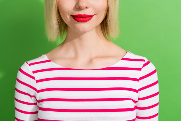 特写裁剪照片，迷人的年轻女孩，红色口红，完美的护肤，填充剂，药物，背景为绿色。图片下载