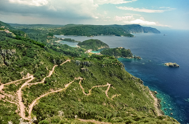 扫描的历史彩色照片，展示了希腊科孚岛帕莱奥卡斯特里察沿海地区的岩石和山脉，阳光明媚。图片下载