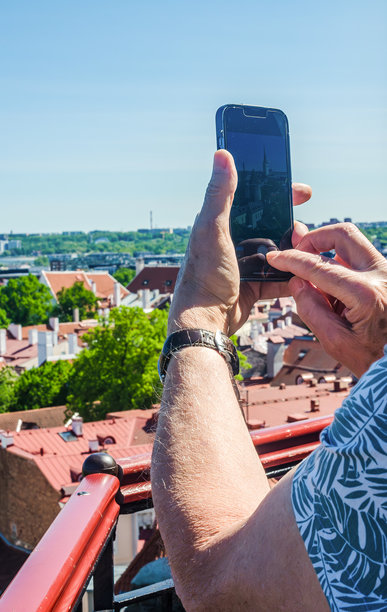 男子在塔林的风景屋顶观景点用智能手机拍摄城市照片图片下载