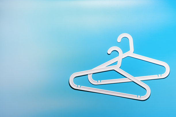 两个白色衣架，现代简约构图，背景为鲜艳的蓝色渐变，塑料架营造出现代简约的美感，俯视图，平铺创意照片，留白空间图片下载