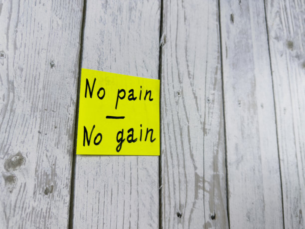 黄色便签纸上写着“没有痛苦就没有收获”，放置在木板上。照片象征着努力和毅力，适合鼓励主题的动机和付出。图片下载