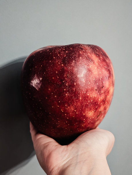 一位女性手中握着一个大红苹果的竖版照片图片下载