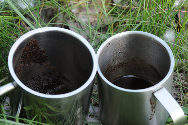 两只金属咖啡杯放在草地上，特写照片图片下载