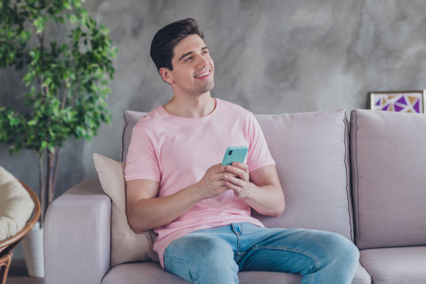 穿着休闲服的网红男士坐在沙发上，沉思着发布概念，身处舒适的公寓室内。图片下载