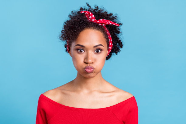 穿着红色露肩衬衫、脸颊鼓鼓的搞笑非洲女士的照片，背景为蓝色。图片下载