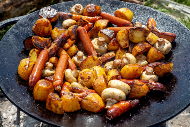 铁铸平底锅上烤制的香菇、香肠和土豆。夏季自然中的野餐。食物的横向照片。图片下载