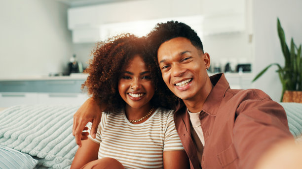 在家中的沙发上，情侣们一起自拍微笑，留下美好的回忆。亲密、爱情和照片，适合社交媒体或个人资料照片更新的视角。图片下载