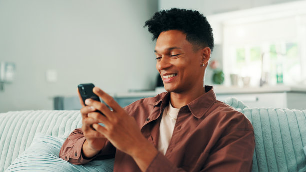 在线约会，男人在家中通过社交媒体应用和订阅进行手机短信交流，周末注册，科技或男性在沙发上发送手机信息，用于发布、聊天和新闻网站。图片下载