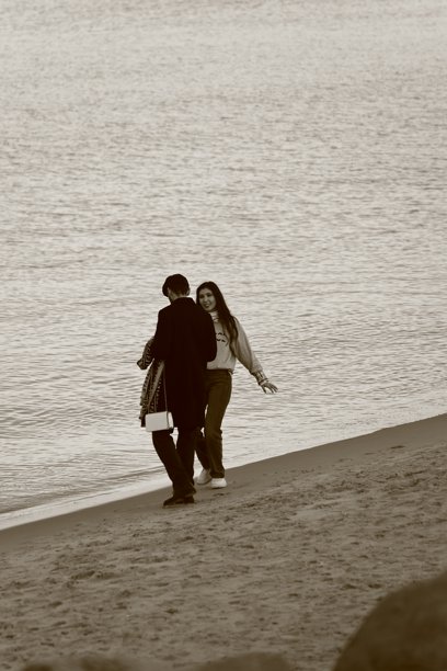 海滩上微笑着看着朋友的女人，棕褐色照片图片下载