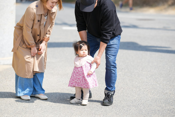 日本家庭在初春的城镇散步：一对三十多岁的父母和他们一岁的女儿。温馨的日常时刻，城市环境中的专业家庭照片。图片下载