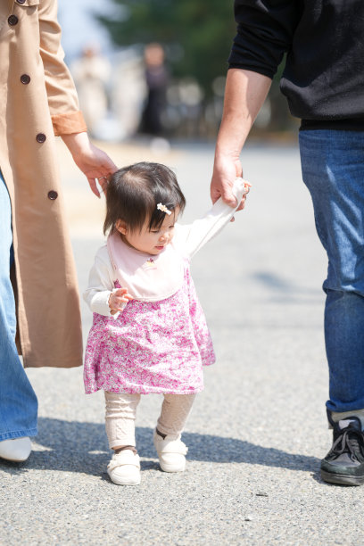 日本家庭在初春的城镇散步：一对三十多岁的父母和他们一岁的女儿。温馨的日常时刻，城市环境中的专业家庭照片。图片下载