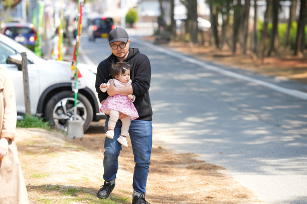 日本家庭在初春的城镇散步：一对三十多岁的父母和他们一岁的女儿。温馨的日常时刻，城市环境中的专业家庭照片。图片下载
