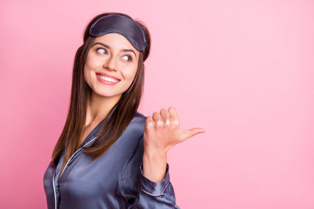 女孩在粉色背景下指着背后空白处，做出竖大拇指的姿势的照片肖像图片下载