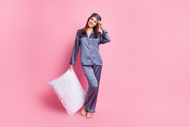 迷人女孩一只手抱着枕头的照片肖像，背景为柔和的粉色。图片下载