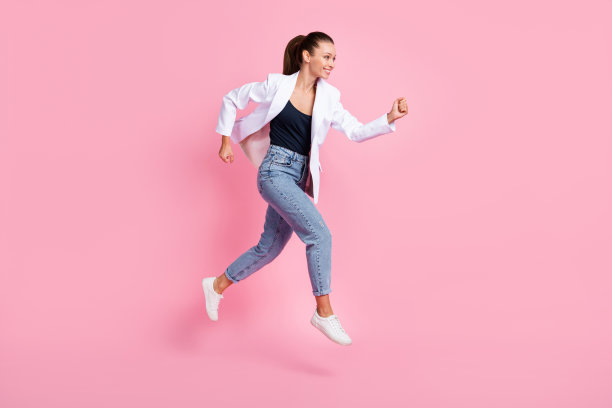 漂亮女士在粉色背景上跳跃奔跑的全身侧面照片，周围空旷。图片下载
