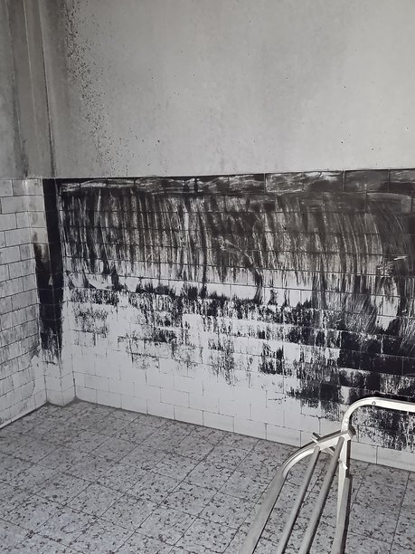 烧焦的浴室内部的竖版照片，白色瓷砖上有黑色火灾污渍。图片下载