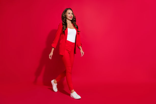 甜美的棕发女士穿着西装鞋，站在红色背景前的全身照片图片下载