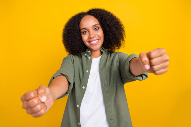 乐观的年轻棕发女士穿着卡其色衬衫，驾驶时的照片，背景为黄色。图片下载
