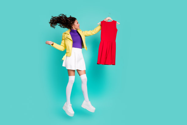 年轻快乐女孩的全身侧面照片，展示新秋季系列服装，购物者，背景为青绿色。图片下载