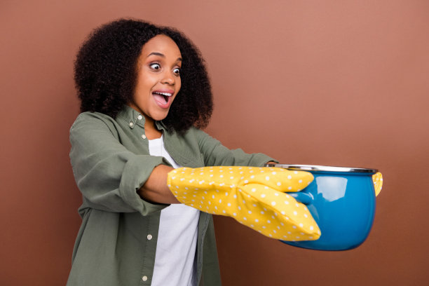 穿着卡其色衬衫的时尚棕发年轻女性在棕色背景下做饭，留有空白空间的个人资料照片图片下载