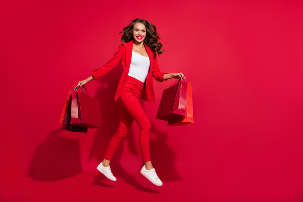 穿着西装鞋子的可爱棕发女士在红色背景上跳跃的全身侧面照片图片下载