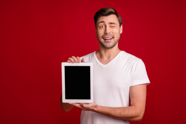 年轻企业家的照片肖像，展示平板电脑屏幕，留白，眨眼，背景为鲜艳的红色。图片下载