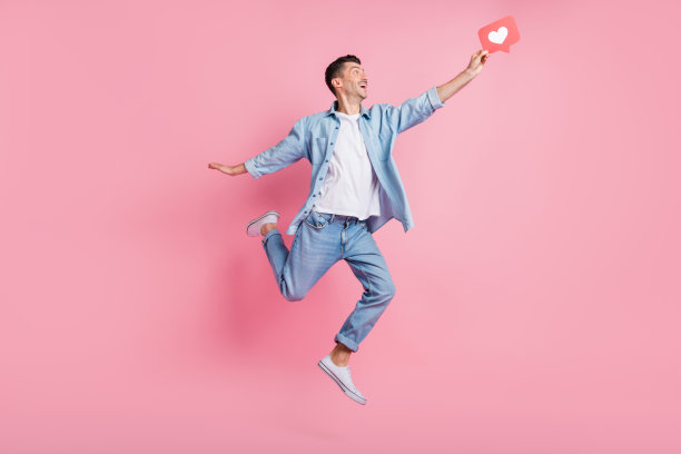 全身照片，快乐的男人像图标一样跳起，背景为柔和的粉色。图片下载