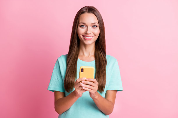 愉快的女性在粉色背景下用智能手机阅读社交媒体的照片肖像图片下载