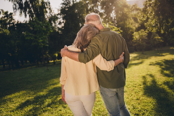 老年人灰发男女在公园户外和谐相拥的背面脊柱视角照片图片下载