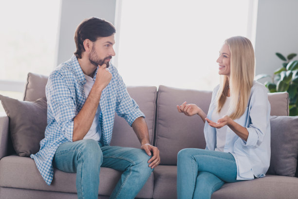 可爱的年轻情侣的个人照片，棕发男孩和金发女孩穿着白衬衫和牛仔裤，坐在室内的客房里。图片下载