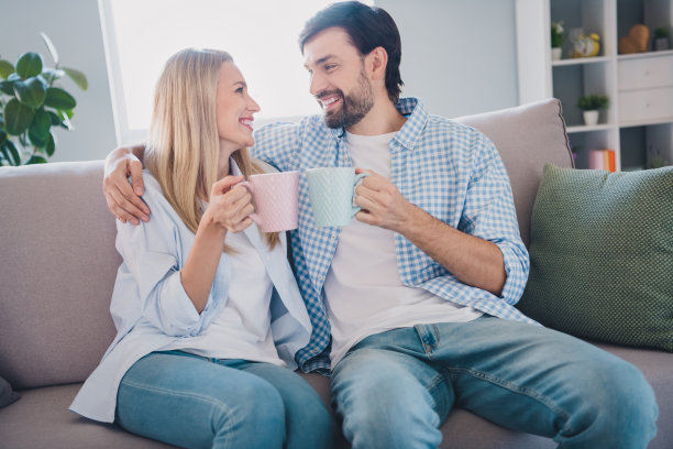 快乐的情侣在室内沙发上享受美味的早晨美式咖啡侧面照片图片下载