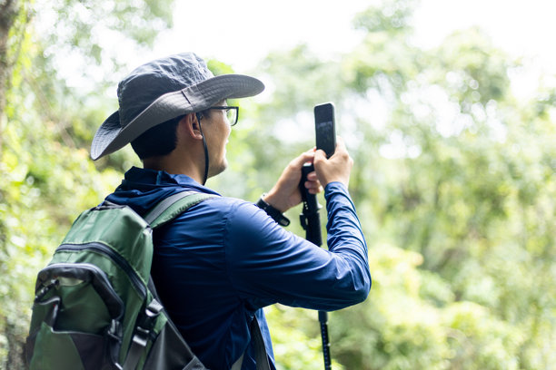 男子在森林公园徒步旅行，用手机拍摄风景照片图片下载